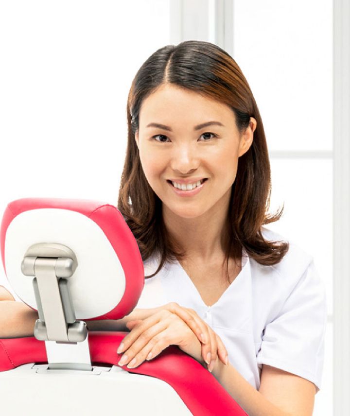 Portrætbillede af unge kvinde der smilende sidder i en tandlægeunit
